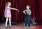 Young Boy Clown Aiming Large Gun at Blond Girl