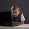 Young boy with computer. funny child looking in notebook