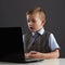 Young boy with computer. funny child looking in notebook