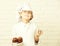 Young boy cute cook chef in white uniform and hat on stained face flour with glasses holding chocolate cakes on plate