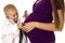 Young boy doctor with stethoscope on pregnant moms belly close