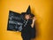 Young boy dressed as a magician is holding happy halloween chalkboard