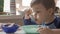 Young Boy Eats Soup Sitting At Dining Room Table