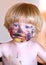 Young boy with face covered in colourful paint