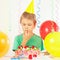 Young boy in festive hat tasting birthday cake