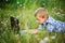 Young boy in field with dandelions with a laptop