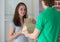 A young boy food delivery sender arrives at the customer`s place and sends a paper bag for the client. They smile at each other.