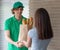 A young boy food delivery sender holding a grocery paper bag arrives at the customer`s place and sends a paper bag for the client