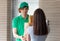 A young boy food delivery sender holding a grocery paper bag arrives at the customer`s place and sends a paper bag for the client