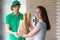 A young boy food delivery sender holding a grocery paper bag arrives at the customer`s place and sends a paper bag for the client