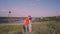 Young boy and girl come together, in center of the frame,kiss, bridge, river, trees, grass, nature, against the