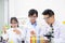 Young boy and girl doing science experiment with colorful liquid chemical inside glass tube and beaker. With teacher who teach and