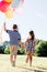 Young boy and a girl running with a bunch of colorful balloons.