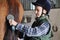 Young boy is grooming the horse