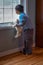 young boy with his stuffed bear, looking out the window