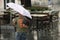 Young boy holding a basketball walking under umbrella on a rainy  day in the city street