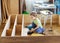 Young boy holding screwdriver while sitting on floor at unfinished shelf unit