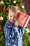 Young Boy Holding Wrapped Present In Front Of Tree