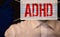 Young boy holds ADHD text written on sheet of paper. ADHD is Attention deficit hyperactivity disorder