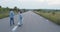 Young boy holds his girl the hand and helps skateboarding on road