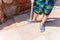 Young boy hosing the sand off himself and his shoe