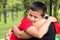 Young boy hugging his mother in the park with closed eyes and smiling, happy and tender childhood/parenting moment