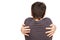 Young boy hugs himself on a white background. Rear view