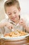 Young boy indoors eating fish and chips