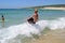 Young boy jumping into wave on a sunny beach