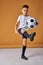 Young boy kneeing a soccer ball isolated in studio