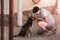 Young boy kneels next to a brown dog holding a ball in his hand, playing with his dog