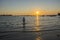 Young boy licking their feet on the beach at sunset