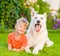 Young boy lying with White Swiss Shepherd dog on green grass