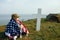 A young boy in a military cap, covered by the flag of the united states sitting on the grave of his deceased father. May 27th