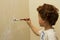 Young boy painting a wall in a room