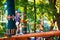 Young boy passing the cable route high among trees, extreme sport in adventure park