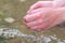 Young boy playing with clear water at a little creek using his hands and the water spring cooling his hands and refreshing