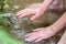 Young boy playing with clear water at a little creek using his hands and the water spring cooling his hands and refreshing