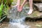 Young boy playing with clear water at a little creek using his hands and the water spring cooling his hands and refreshing