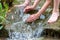 Young boy playing with clear water at a little creek using his hands and the water spring cooling his hands and refreshing