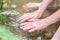 Young boy playing with clear water at a little creek using his hands and the water spring cooling his hands and refreshing