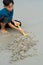 A young boy playing sand at the beach. using yellow shovel