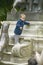 Young boy playing on statue in park, Paris, France