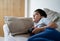 Young boy playing video games online, Candid shot Happy mixed race child lying on sofa holding game console. Portrait  kid face