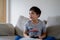 Young boy playing video games online, Candid shot Happy mixed race child sitting on sofa holding game console. Portrait  kid face