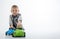 A young boy plays with multi-colored toy cars on a white background. Children\\\'s entertainment, fun