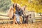 Young boy points in a direction where parents and his sisters look during an autumn walk in the nature with a dog