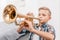 Young boy practicing playing trumpet in living room