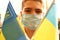 A young boy in a protective mask holds the national flags of Ukraine yellow-blue. Stop coronavirus. Coronavirus pandemic COVID-19