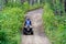 A young boy quads up a hill through the forest